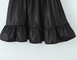Détail du tissu noir à texture craquelée avec ourlet en dentelle blanche sur la robe