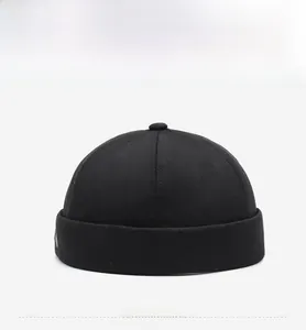 Detailed front view of black cotton docker hat with side embroidery and metal top button