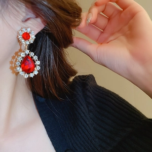 Détail macro de boucles d'oreilles goutte rouge avec strass et base dorée