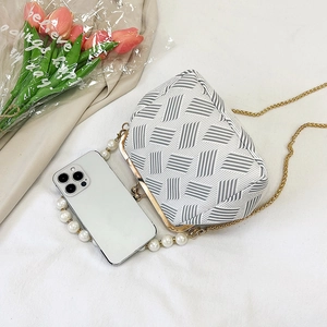 White woven shell bag with gold chain strap and pearl handle on a minimalist background