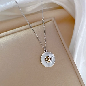 Detail of silver titanium necklace with white shell coin pendant on silk fabric