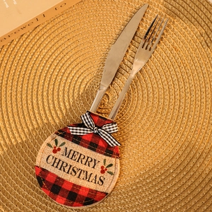 Detail of Christmas plaid cutlery holder with Merry Christmas embroidery on woven placemat