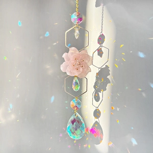 Detail of pink resin flower and crystal beads on a golden suncatcher with rainbow prisms