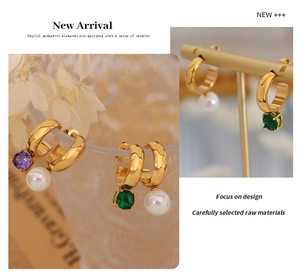 Close-up of gold C-shaped earrings with purple zircon and round pearl drop charms
