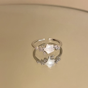 Detailed close-up of a silver star ring with white zircon stones on a reflective surface