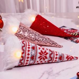 Three glowing Christmas gnomes with knit sequins and LED lights on marble background