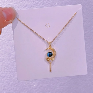 Dettaglio macro della collana con pendente a scettro lunare e perla blu stellata