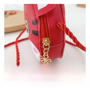 Detail der roten Cartoontasche mit goldenem Blumen-Reißverschluss und geflochtener Kordel