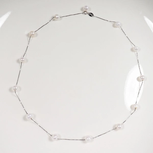 Minimalist S925 silver necklace with white freshwater pearls on a white display plate