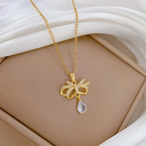 Detail of gold titanium butterfly necklace with zircon drop on luxury beige jewelry box