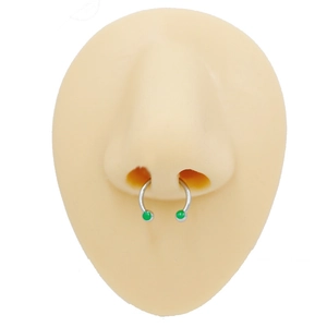 Detail view of silver horseshoe septum ring with green beads on a silicone model