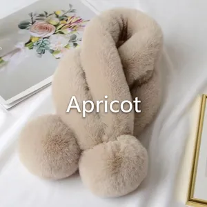 Détail d'une écharpe en fausse fourrure abricot avec pompon doux sur fond de soie élégante