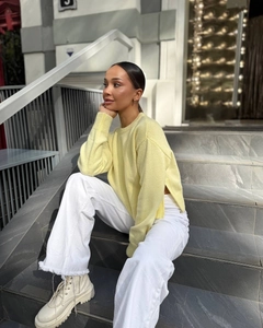 Outdoor shot of light yellow crewneck knit sweater with side slit detail and long sleeves