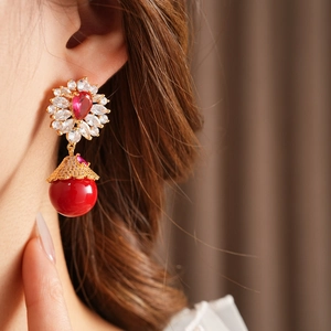Gros plan de boucles d'oreilles vintage en or avec pierres rouges et fleurs en zircon
