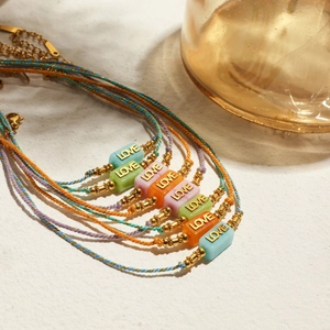 Colorful woven LOVE letter bracelets with gold beads and adjustable cord on stone base