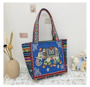 Detail of blue ethnic tote bag featuring elephant embroidery and geometric woven straps