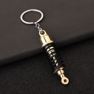 Close-up of car shock absorber keychain with gold finish and black spring on leather
