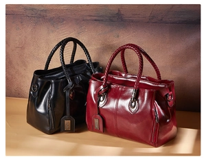 Detail of black and wine red leather Boston bags with woven handles and metal pendants