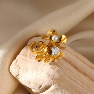 Macro shot of gold floral ring featuring a central pearl and zircon on a textured stone