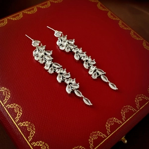 Macro shot of silver leaf tassel earrings with zircon water drops on a red box