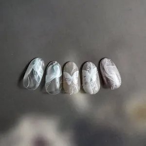Detail of Morandi grey nail art showing hand-painted white butterflies and smoke texture