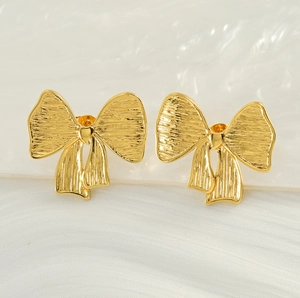 Détail de boucles d'oreilles nœud en or 18K avec finition texturée et rubans