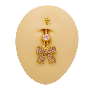 Close-up of golden belly ring with pink crystal and rhinestone bow on a silicone model