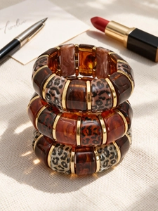 Close-up of three stacked leopard print resin and 18k gold plated elastic bracelets