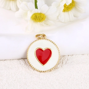 Close-up of a 18k gold plated round pendant with a red enamel heart and daisy flower decor