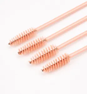 Close-up of four disposable spiral eyelash brushes with peach pink handles and nylon bristles
