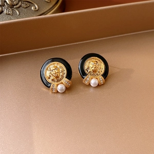 Macro detail of vintage gold lion head earrings with black enamel and white pearl drops