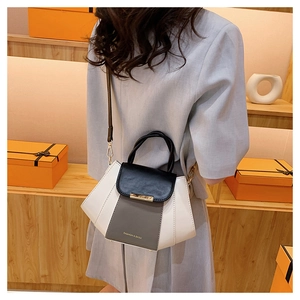 Close-up of contrast-color leather handbag with metal chain strap and luxury lock detail