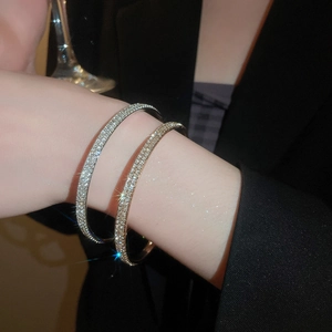 Close-up of elegant gold and silver paved crystal bangles worn with a black blazer