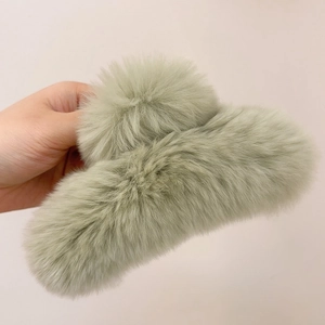 Detailed close-up of a soft sage green faux fur hair claw clip with fluffy texture