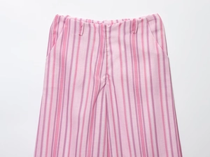 Detailaufnahme der rosa-lila vertikal gestreiften Hose mit Reißverschluss und Stofftextur