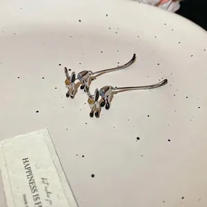 Silver rabbit stud earrings with black enamel accents on a white ceramic display plate