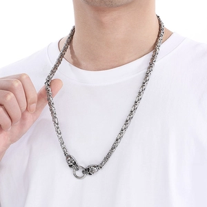Men's hip hop silver Byzantine chain necklace with skull head accents worn on white tee