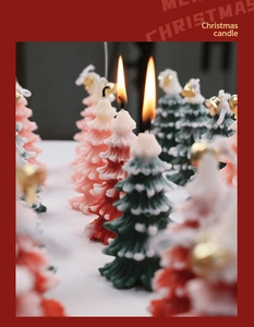 Macro shot of green and pink Christmas tree shaped candles with festive golden bells
