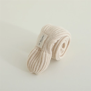Close-up of thick ribbed knit fabric and brand label on a beige baby winter scarf