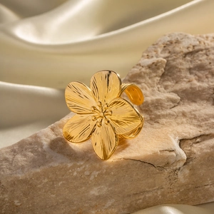 Detailed macro of vintage gold flower ring with textured petals on beige stone