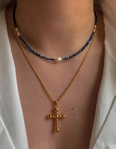 Détail de colliers superposés avec perles bleues facettées et un pendentif croix dorée