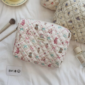 Gros plan d'une trousse à maquillage matelassée aux motifs d'ours et détails dorés chics