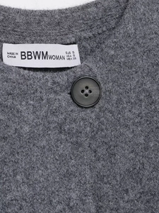 Detail of dark grey knit cardigan showing matte black button and BBWM brand label