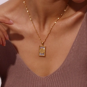 Dettaglio macro della collana placcata oro 18K con ciondolo rettangolare in madreperla e moneta