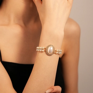 Gros plan d'un bracelet double rang de perles avec perle ovale et détails en strass