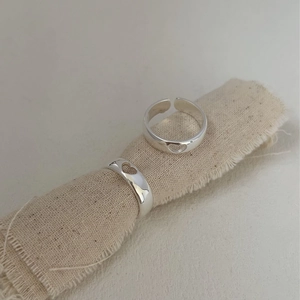 Minimalist 925 sterling silver hollow heart rings on natural fabric background