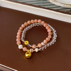 Detailed macro of layered orange moonstone and crystal beaded bracelets with gold charms