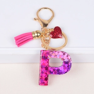 Detail of pink tassel, glitter heart charm and resin letter P keychain with sequins