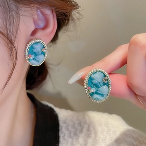 Gros plan de boucles d'oreilles camée avec relief bleu et strass scintillants