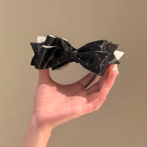 Close-up of a layered black polka dot bow hair clip held to show texture and size